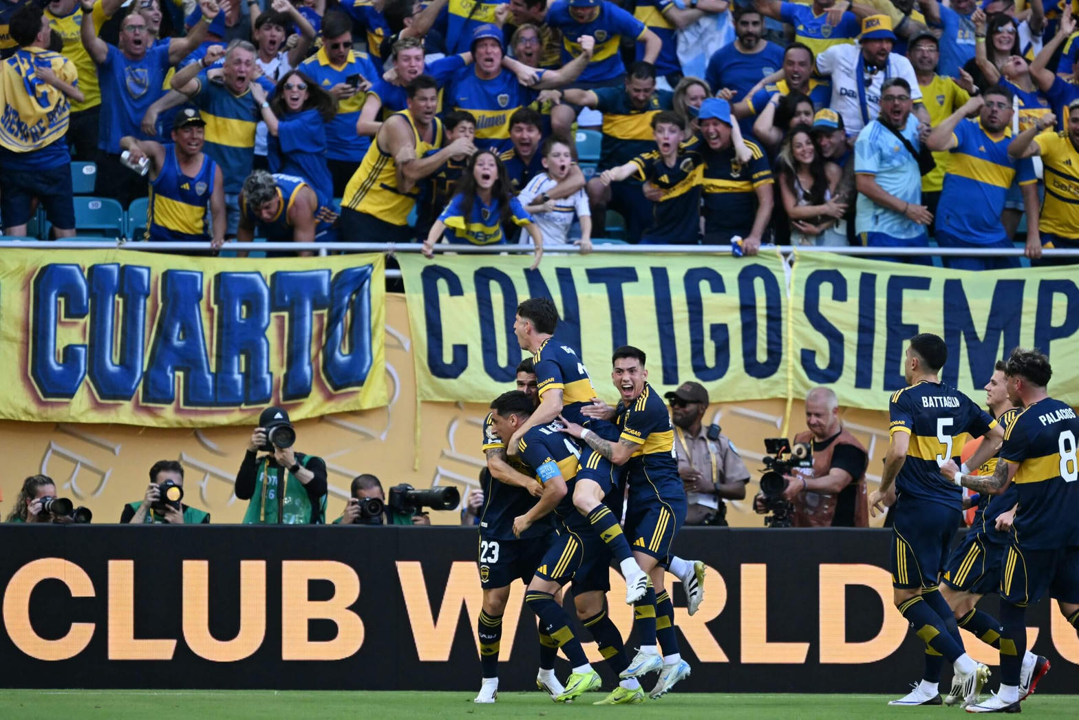 Jugadores de Boca Juniors, de azul y oro, celebran un gol con la hinchada atrás