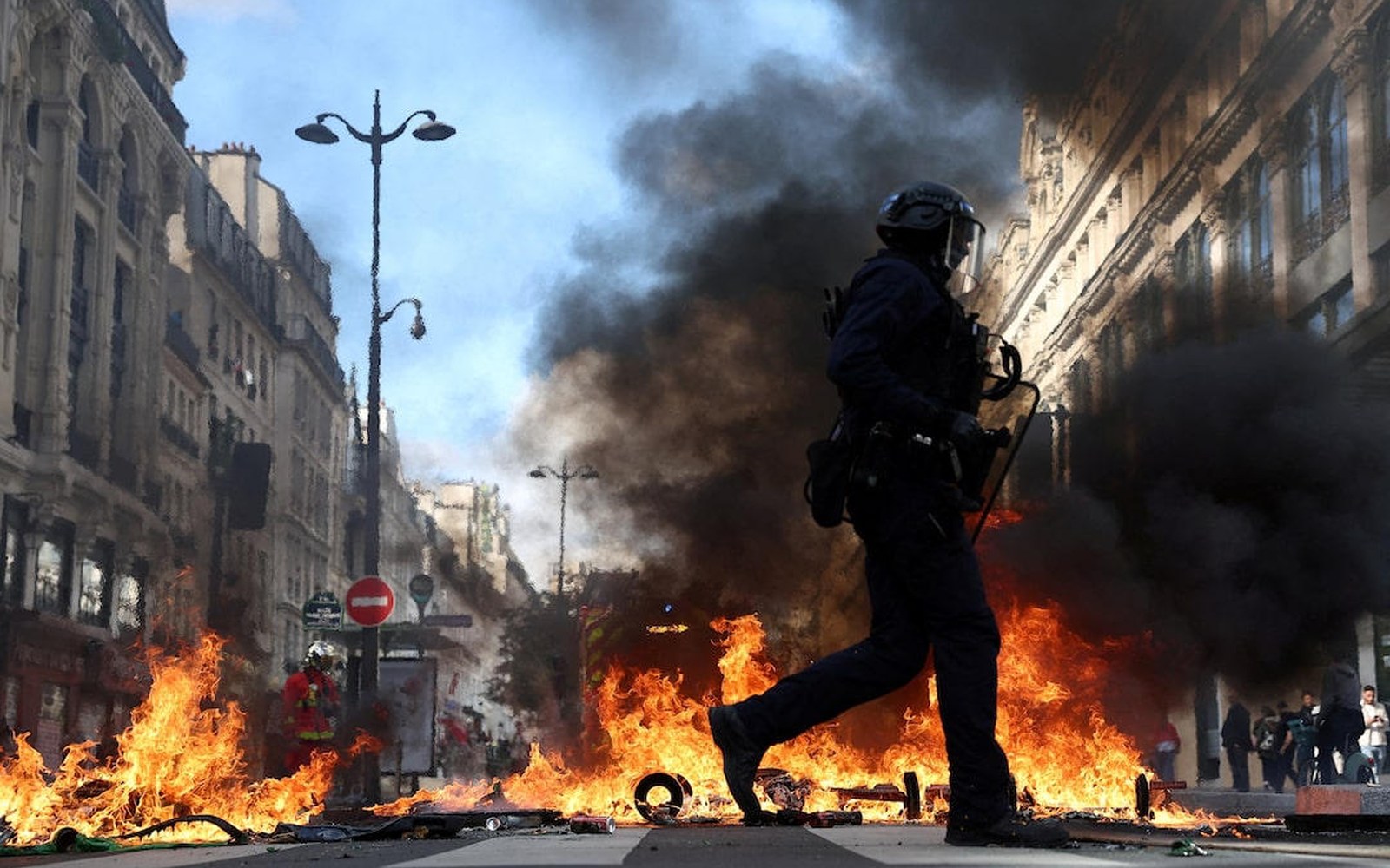 Un policía corre junto a una barricada en llamas en una calle de Francia