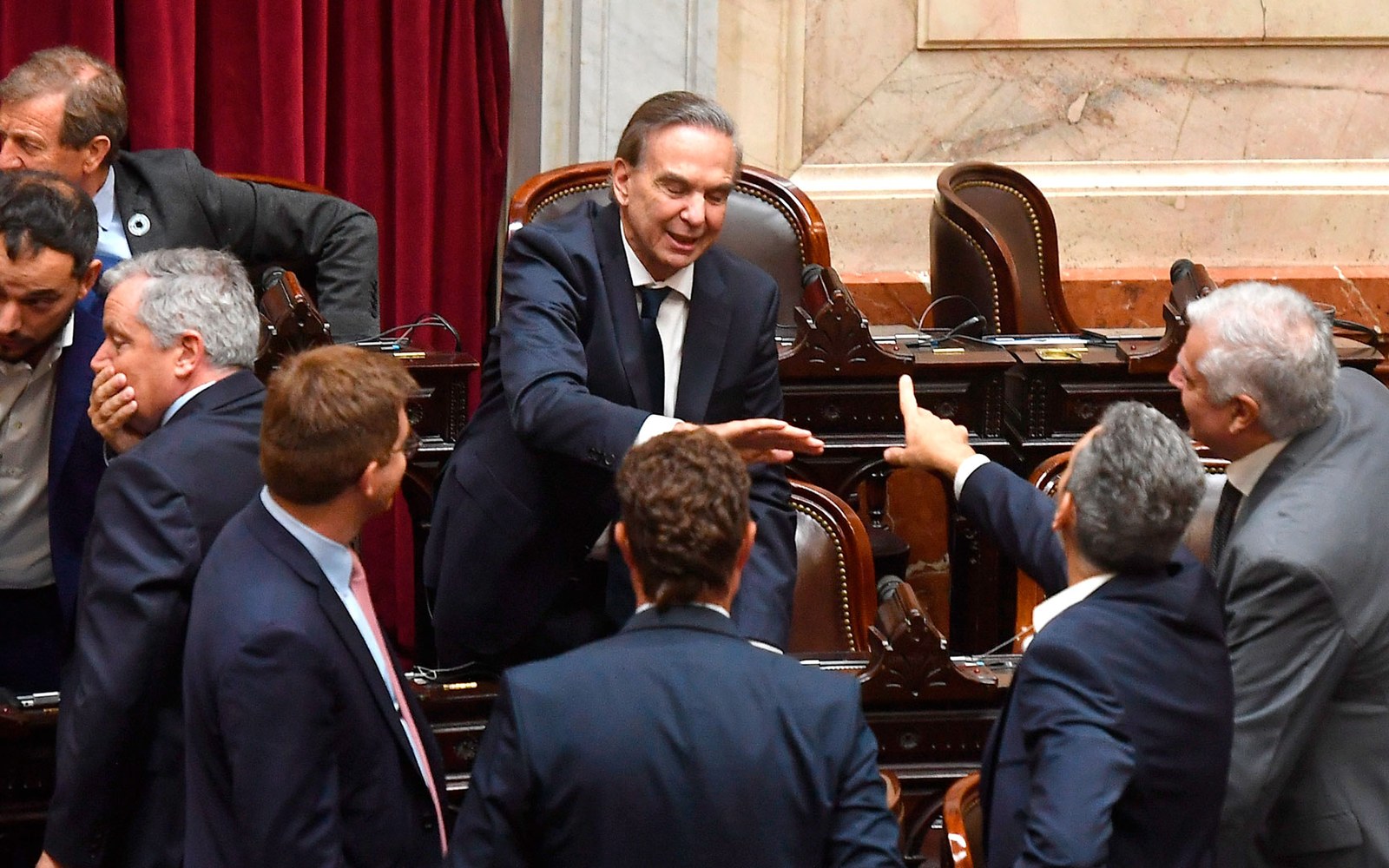 Miguel Ángel Pichetto en el recinto de Diputados, en su banca, hablando con otros diputados